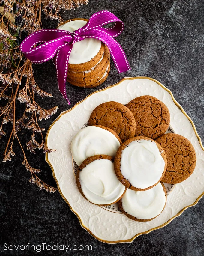 Old fashioned molasses cookies on a plate with a stack beside them in a purple ribbon.