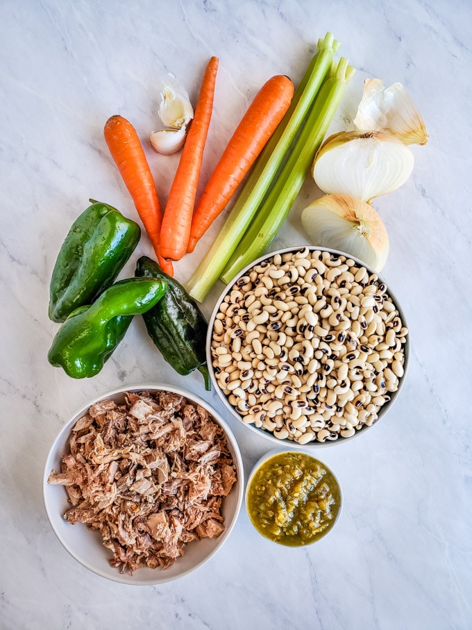 Black-eyed peas in a bowl with pulled pork, poblano chiles, carrots, celery and onion for soup ingredients.