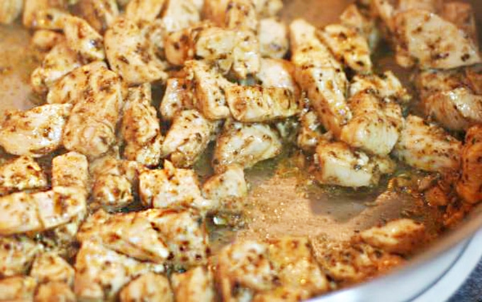 Seasoned chicken in skillet to top Blue Coyote Chicken Nachos