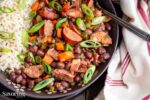 Red beans and rice with scallion garnish in a dark bowl