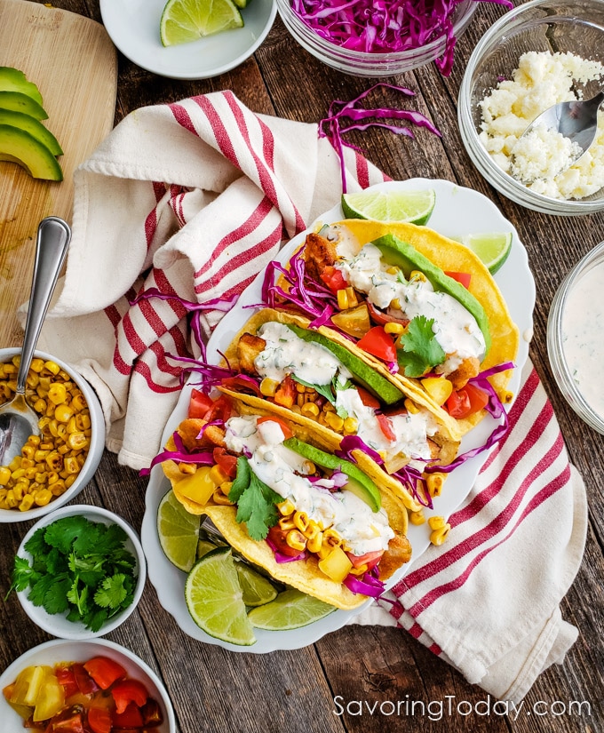 Overhead photo of three fish tacos on a wood table.