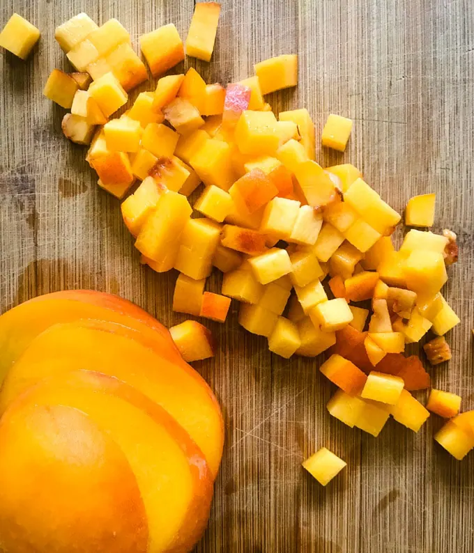 Fresh peach diced for salsa on a cutting board.