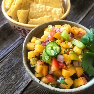 Chunky peach and tomato salsa in a bowl with chips