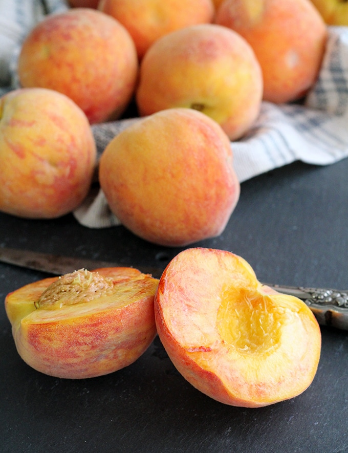 Fresh peaches from the farmer's market cut open on a slate cutting board.