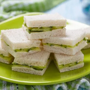 Cucumber tea sandwiches stacked on a plate.