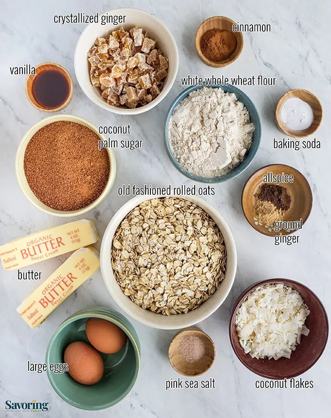 A birds eye view of all the gathered ingredients used for oatmeal cookies in bowls including butter, sugar, oats, eggs, and flour.