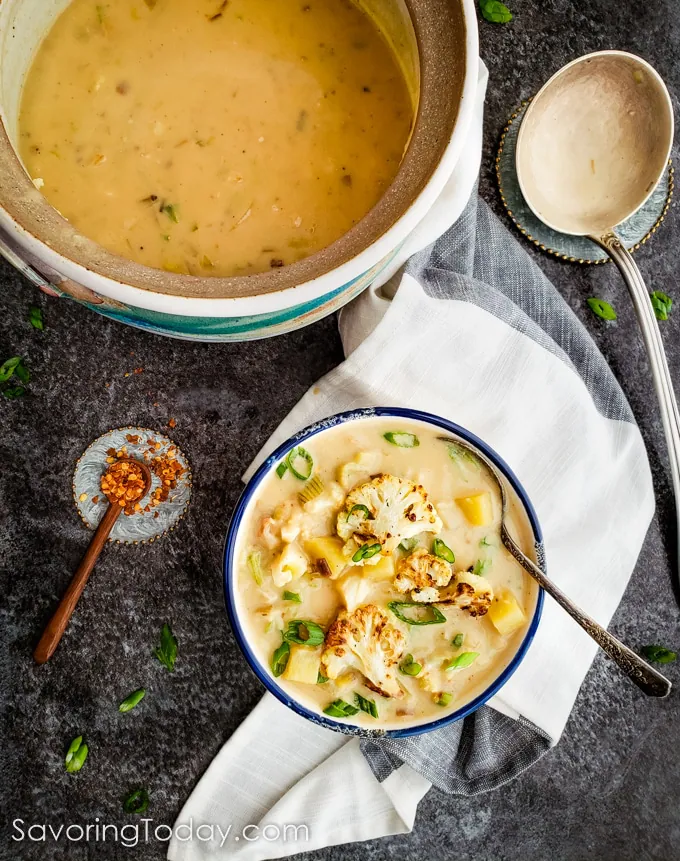 Cauliflower potato leek soup in a bowl beside a soup taurine and ladle.