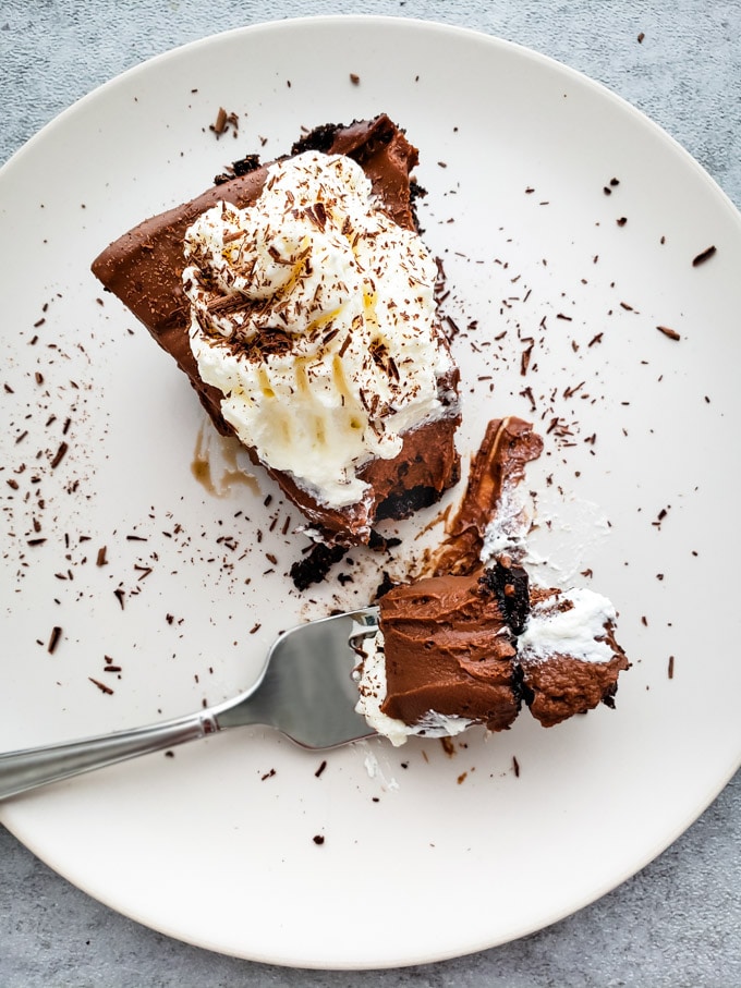A bird eye view of a piece of chocolate pie with whipped chream with a fork and a resting bite