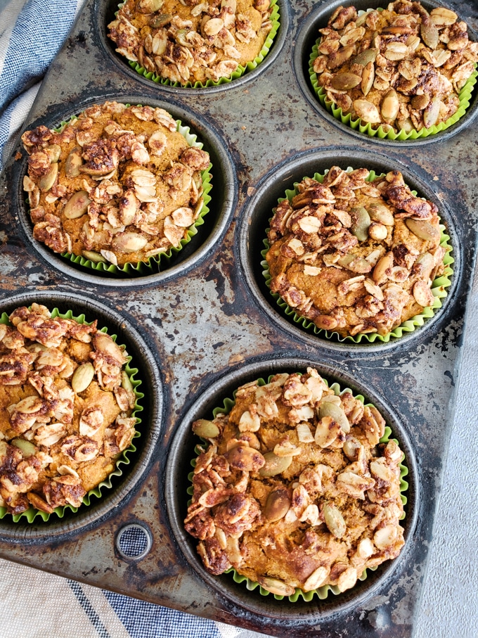 Pumpkin spice muffins in green muffin cups in a tin pan.
