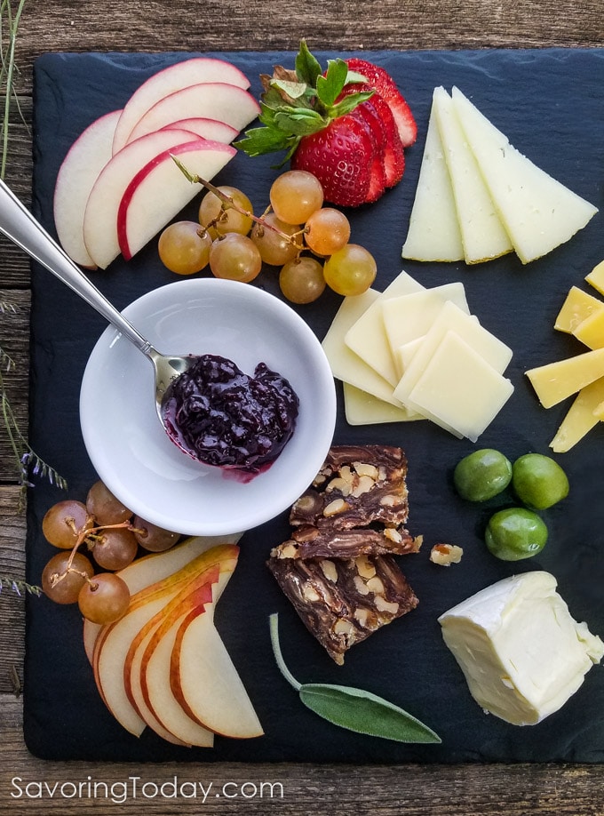 cheese, pear, walnut-date loaf, grapes, apples, and jam on a slate charcuterie board