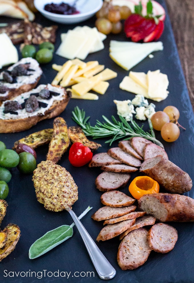 sausage, cheese, potato, olives, grapes, mustard, and mushroom bruschetta on a slate plank
