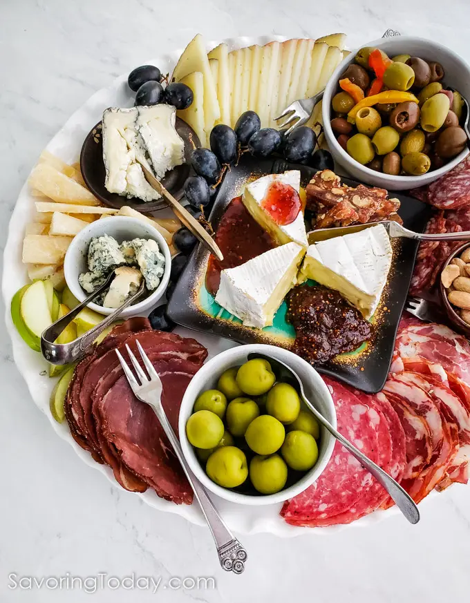 sliced meat, cheese, olives and nuts on a platter for a charcuterie appetizer