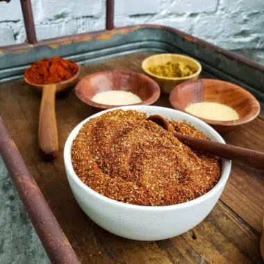 a bowl of chili seasoning mix on a tray with individual spices