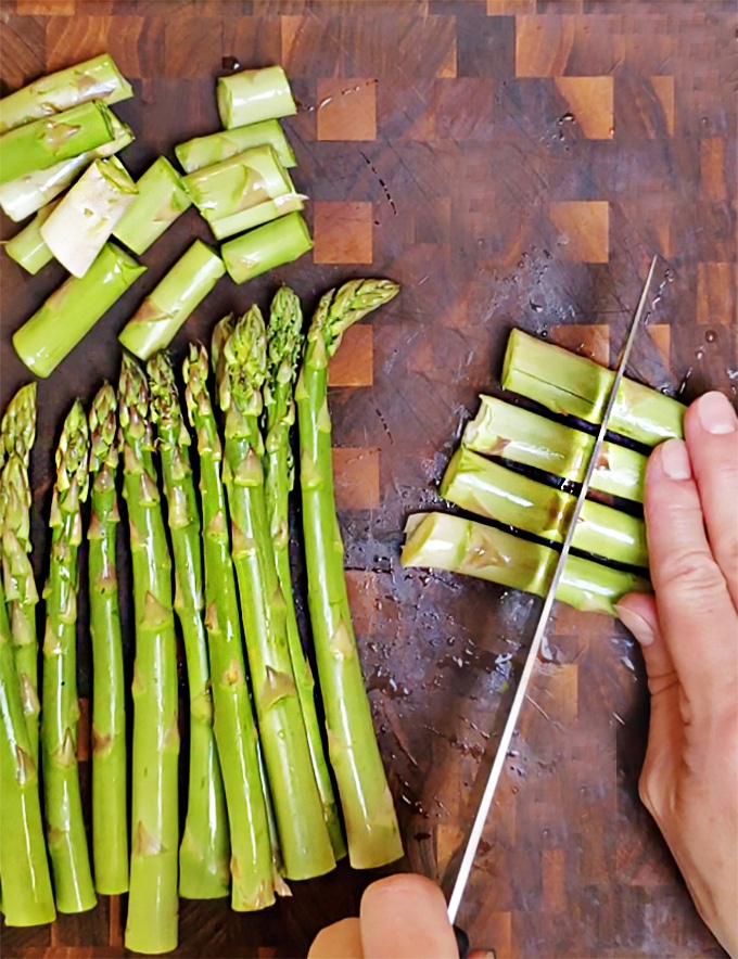 trimming the ends of asparagus on a cutting board