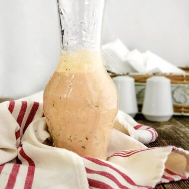 Creamy Russian Salad Dressing in a bottle on a wood table.