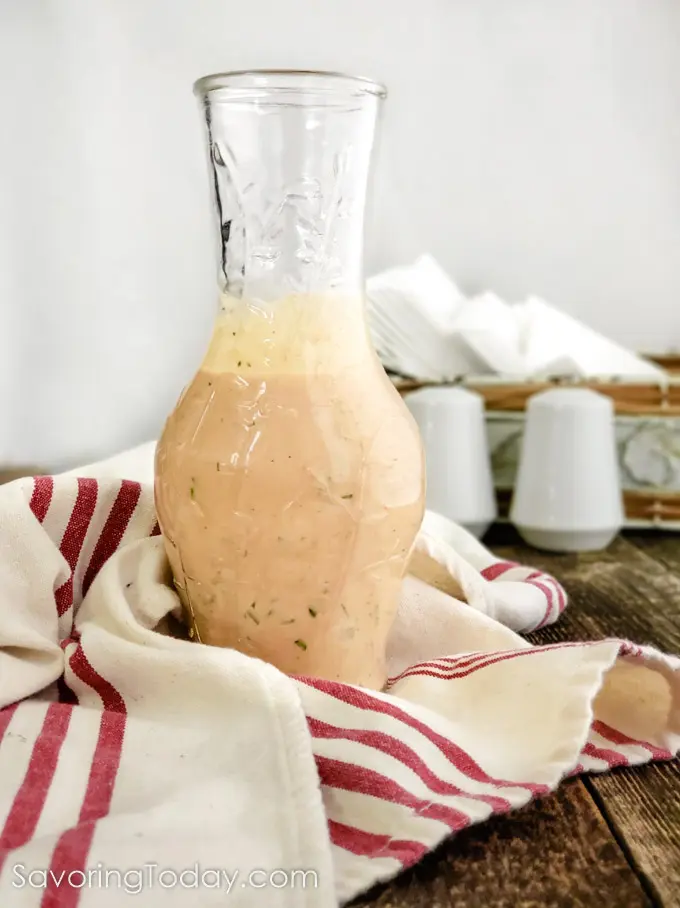 Creamy Russian Salad Dressing in a bottle on a wood table.