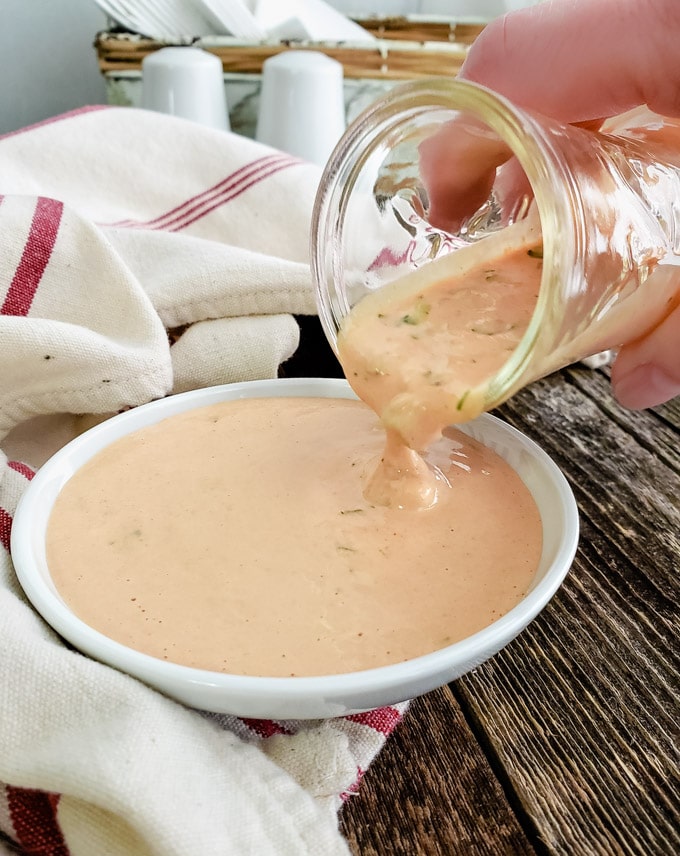Pouring thick creamy dressing out of a jar.