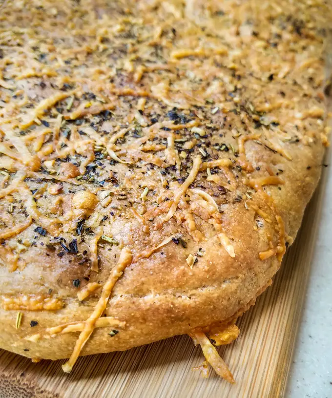 Focaccia flat bread fresh from the oven on a wood board.