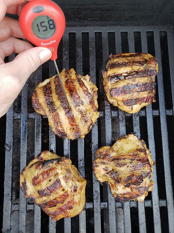 checking the internal temperature of chicken on the grill with thermometer