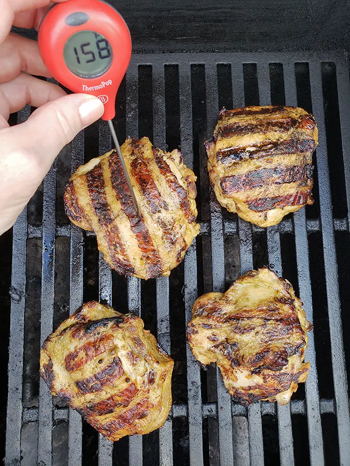 checking the internal temperature of chicken on the grill with thermometer