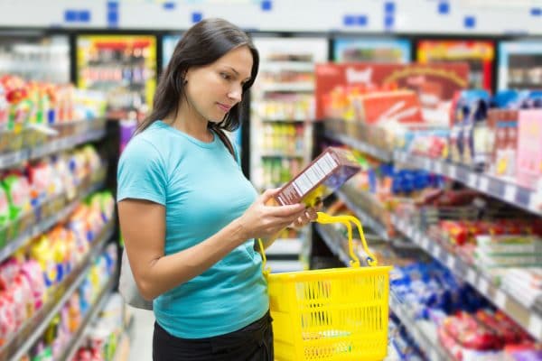Woman reading label on box in grocery store
