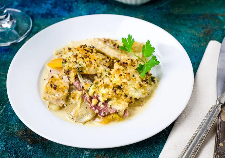 Vegetables and ham in a cream sauce served on a white plate