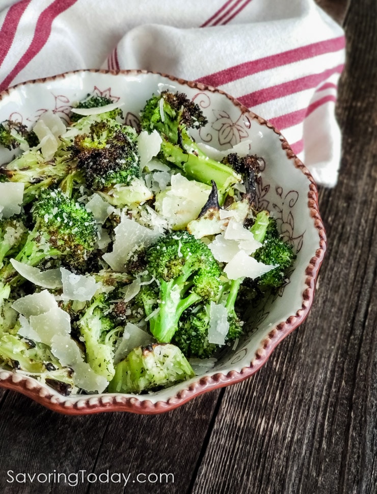 grilled broccoli served in a bowl with shaved parmesan and lemon