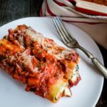 Two cheese and spinach stuffed manicotti with marinara on top