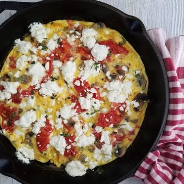 frittata in a cast iron with goat cheese, tomato, and basil