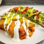 green chicken enchiladas with a salad on a white plate