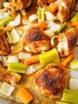 roasted chicken pieces on a pan with celery, carrots, and onions