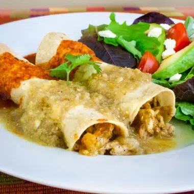 red and green enchilada sauce over chicken enchiladas on a white plate