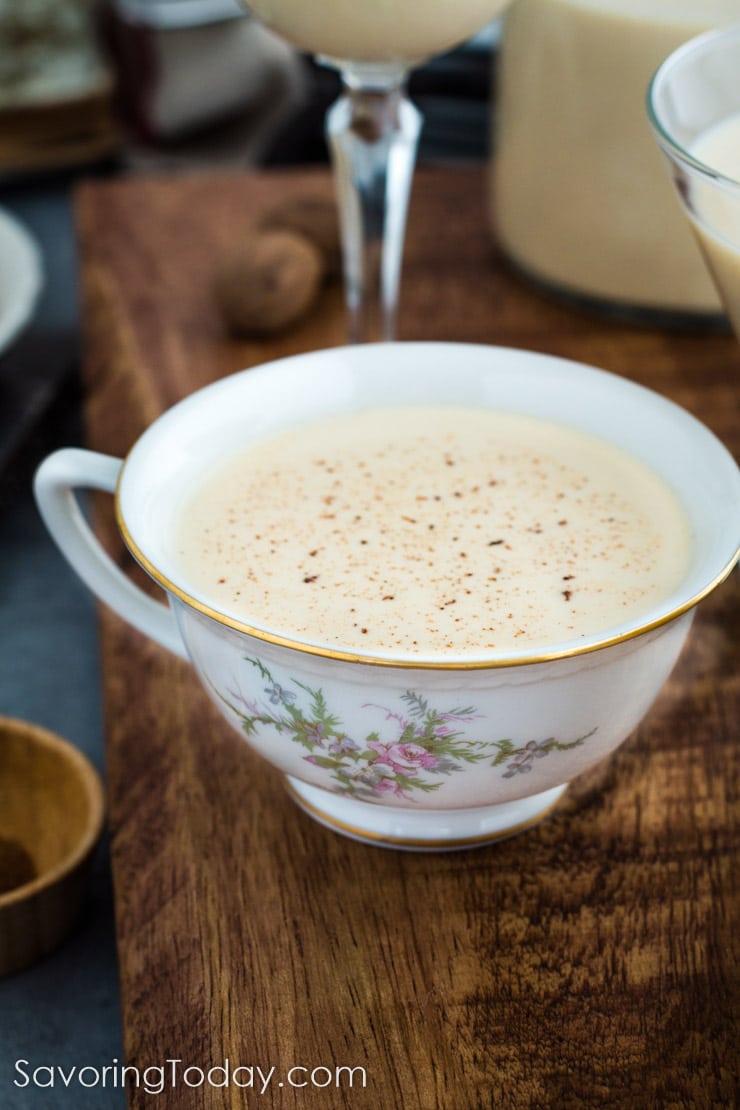 Traditional raw homemade eggnog garnished with freshly zested nutmeg in a china cup