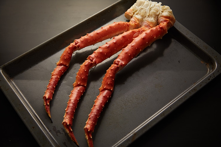 King crab legs on a sheet pan prepared for cooking in the oven