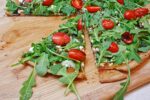 thin crust pizza with arugula and tomatoes