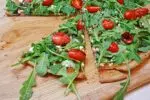 thin crust pizza with arugula and tomatoes