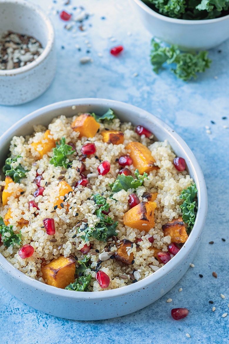 quinoa salad with butternut, kale, pomegranate in a white bowl