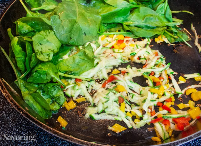 fresh spinach, zucchini, and red pepper in a skillet