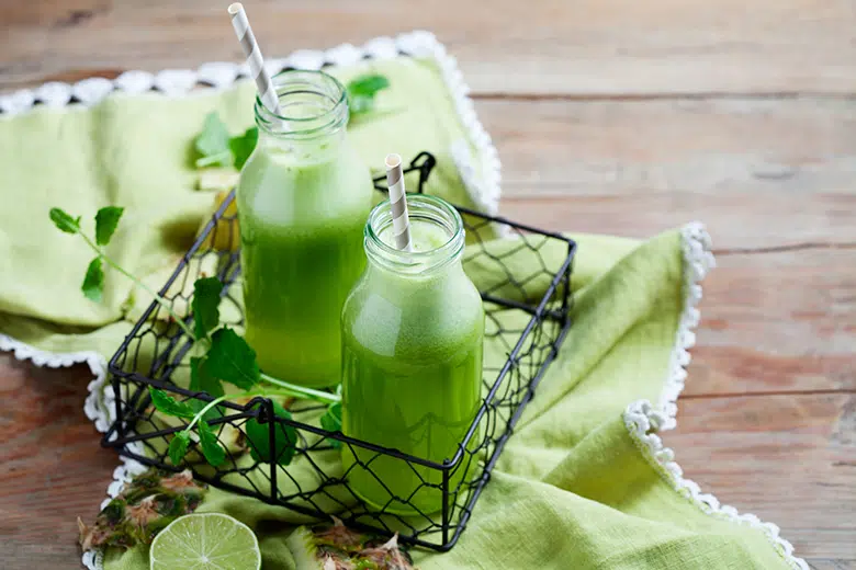 green juice in two jars inside a wire basket