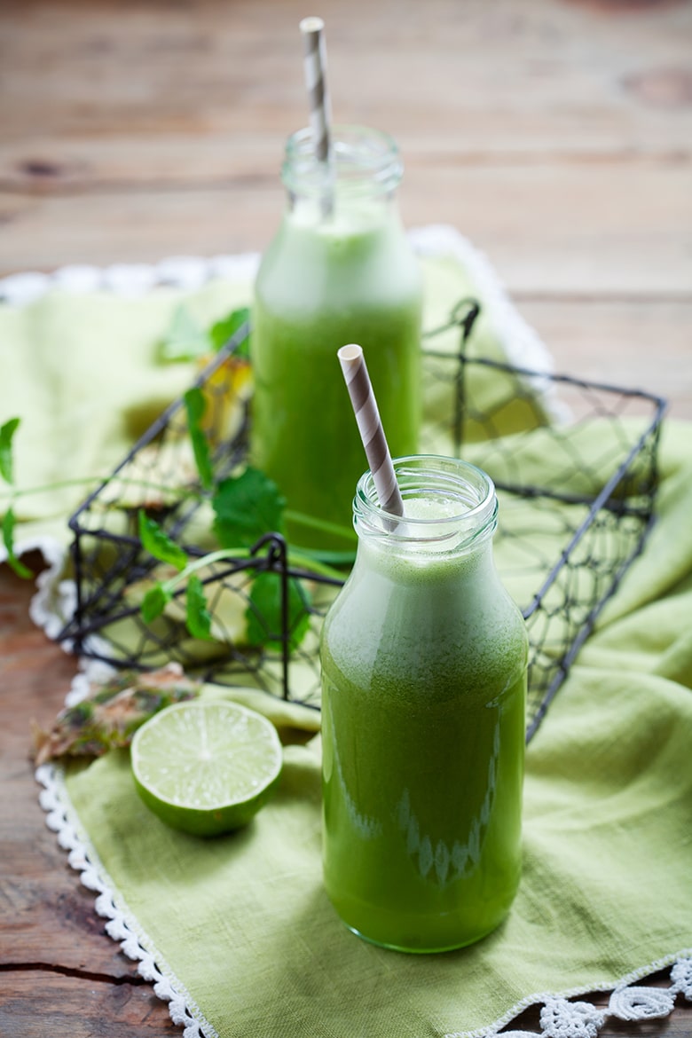 fresh green juice in a jar with straw on a light green napkin