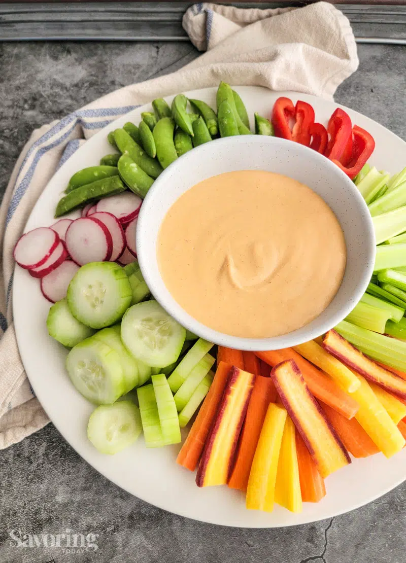 Miso-yogurt dip in the center of a veggie tray with celery, cucumber, carrots and radishes.
