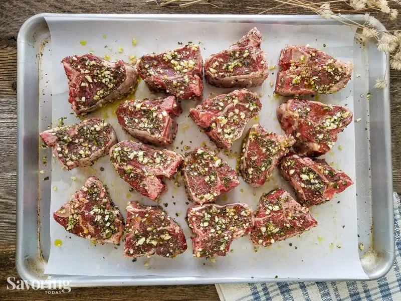 lamb marinating on a parchment lined baking sheet