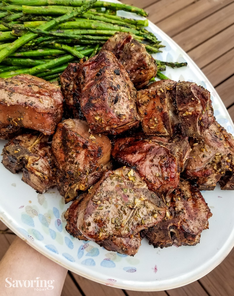grilled lamb chops piled on a platter with grilled asparagus