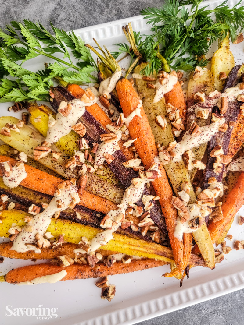 Roasted carrots drizzled with sauce on a white platter