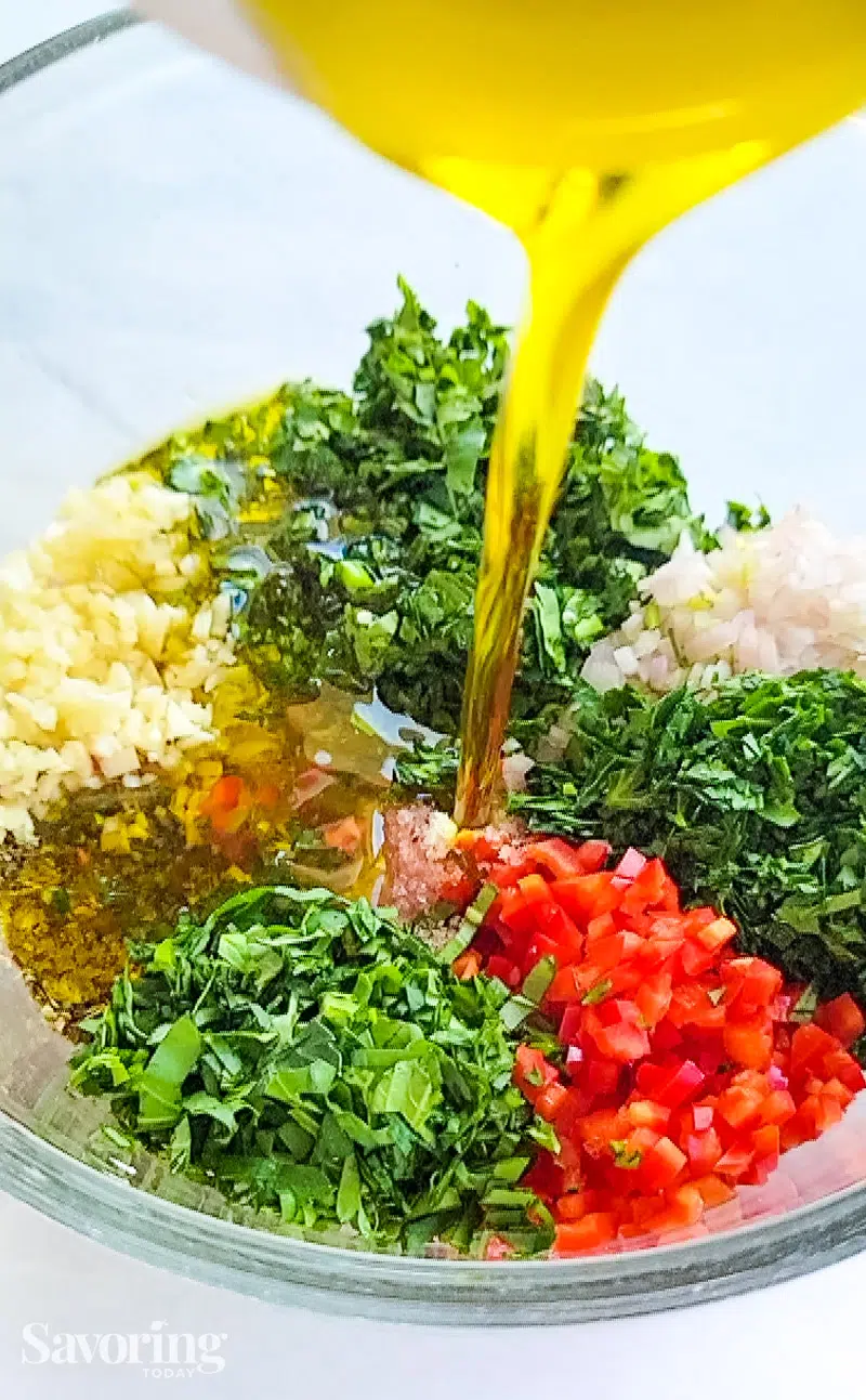 pouring oil into chimichurri herbs