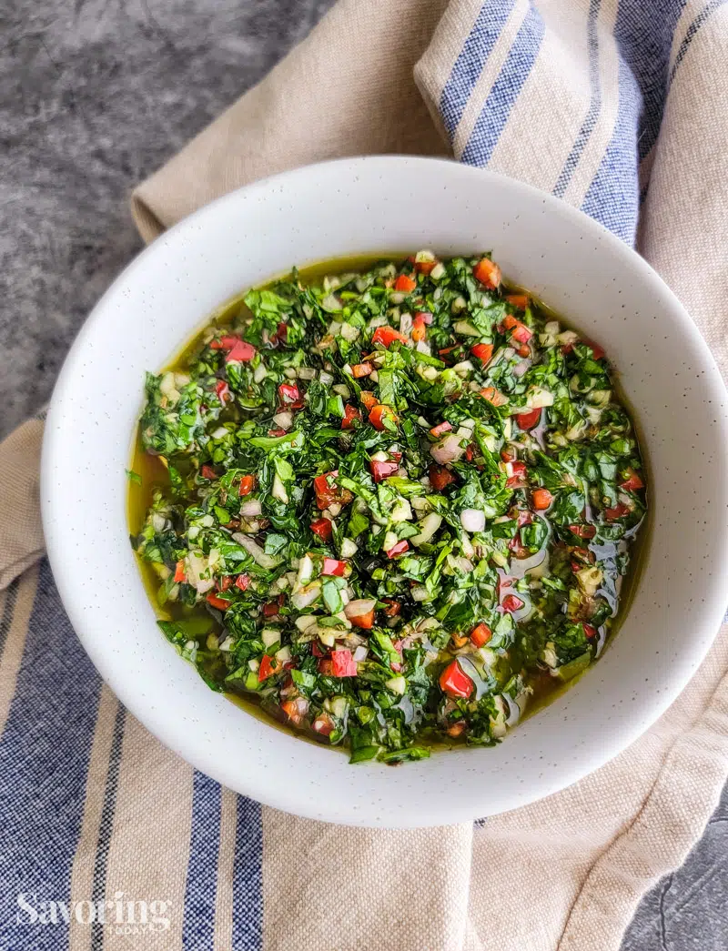 chimichurri sauce in a white bowl on a towel