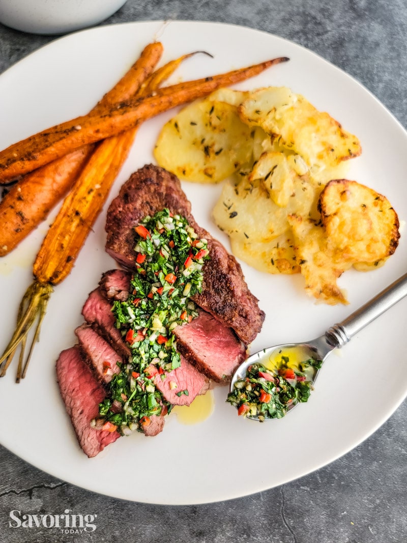 Chimichurri sauce on steak with carrots and potatoes