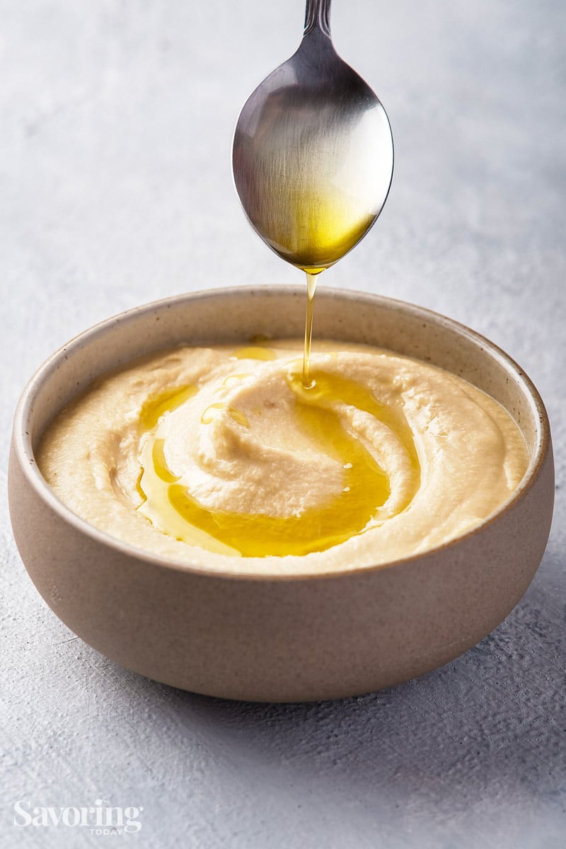 Garnishing hummus with olive oil with a spoon