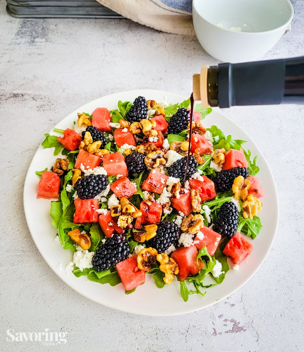 Drizzling balsamic dressing over a watermelon salad