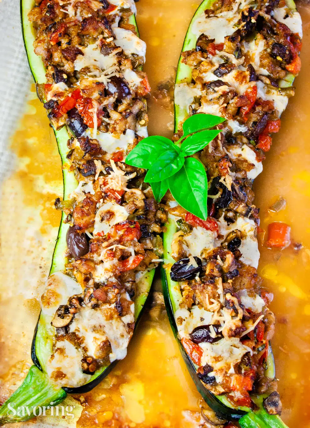 Zucchini stuffed with sausage, cheese, and olives with basil on top